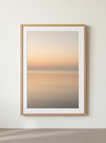 Ingelijste Print Horizon Zonsopgang - grote ingelijste horizonprint in abrikoos en zand van Dekovira, tegen een warmwitte muur in daglicht